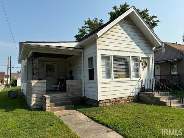 bungalow-style house with a front yard and central air condition unit