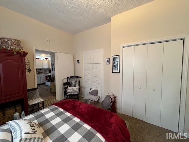 carpeted bedroom featuring a textured ceiling and a closet