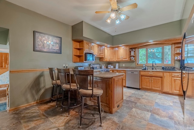 kitchen featuring refrigerator, a kitchen bar, stove, stainless steel dishwasher, and ceiling fan