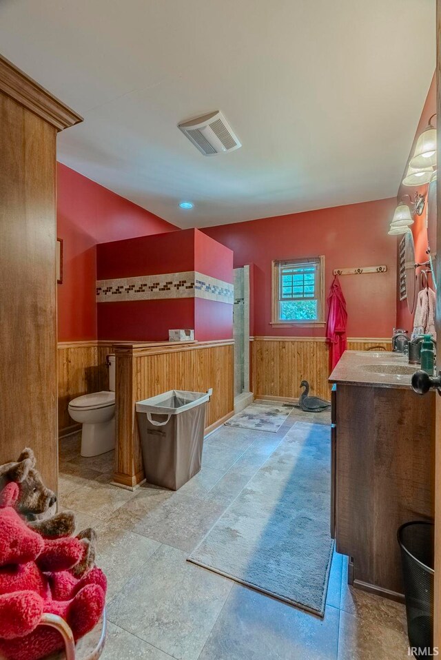 bathroom with vanity, toilet, and wood walls