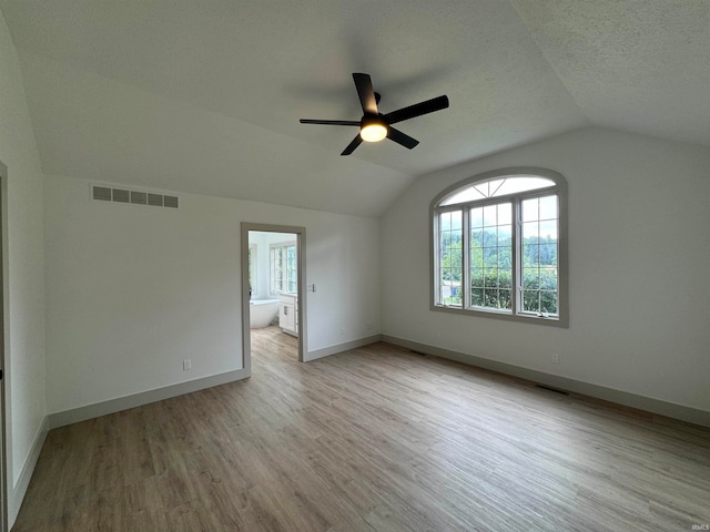 interior space with vaulted ceiling, a textured ceiling, ceiling fan, and light wood-type flooring