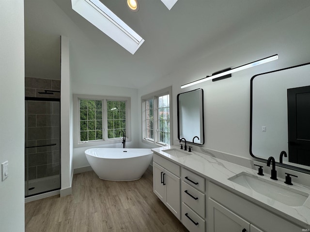 bathroom with dual vanity, shower with separate bathtub, lofted ceiling with skylight, and hardwood / wood-style floors