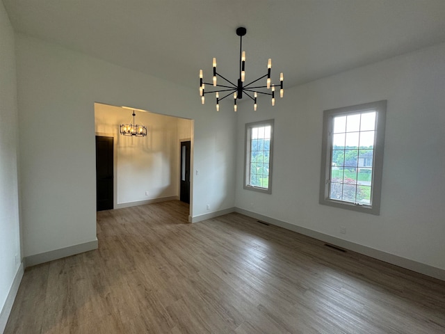 unfurnished room with wood-type flooring and a notable chandelier