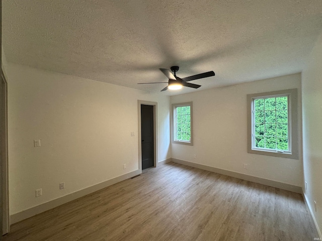 empty room with a textured ceiling, hardwood / wood-style flooring, and ceiling fan