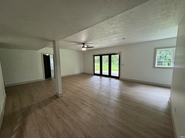 spare room with a textured ceiling, wood-type flooring, ceiling fan, and french doors