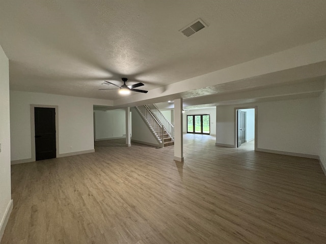 basement with a textured ceiling, wood-type flooring, and ceiling fan