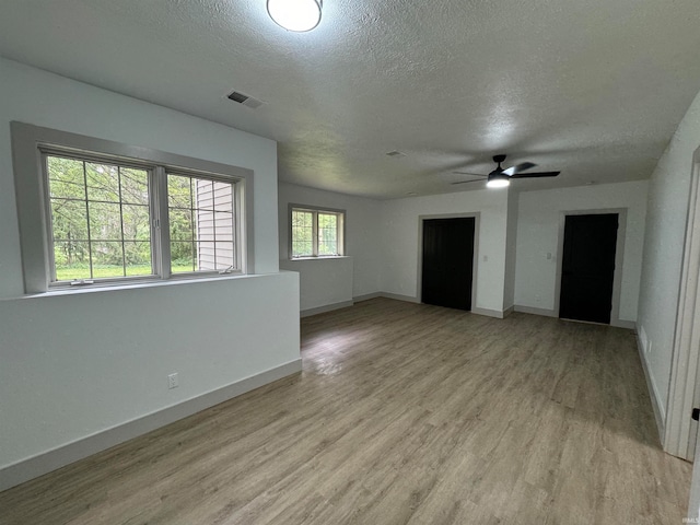 unfurnished living room featuring a textured ceiling, ceiling fan, and light hardwood / wood-style floors