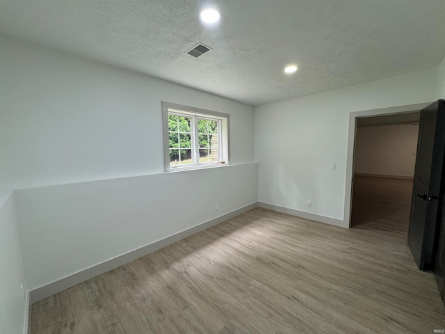 unfurnished room featuring light hardwood / wood-style flooring and a textured ceiling