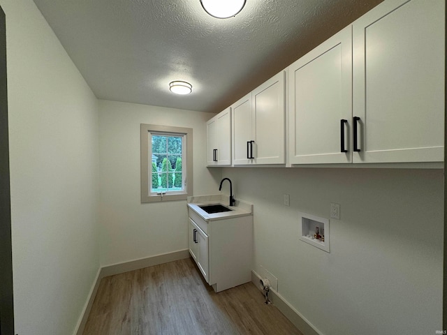 laundry area with sink, cabinets, a textured ceiling, light hardwood / wood-style flooring, and washer hookup