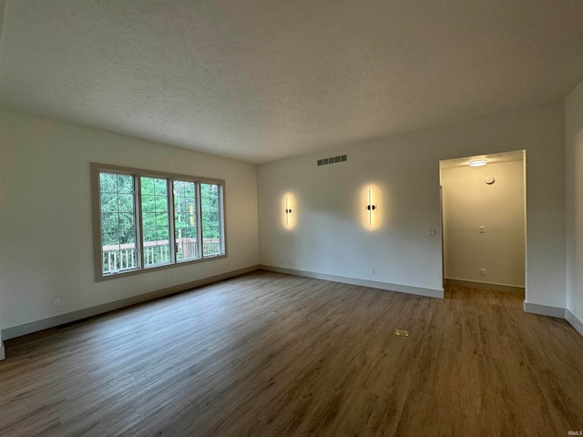 empty room featuring a textured ceiling and hardwood / wood-style flooring