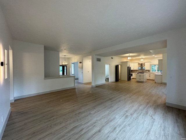 unfurnished living room with a chandelier and hardwood / wood-style flooring