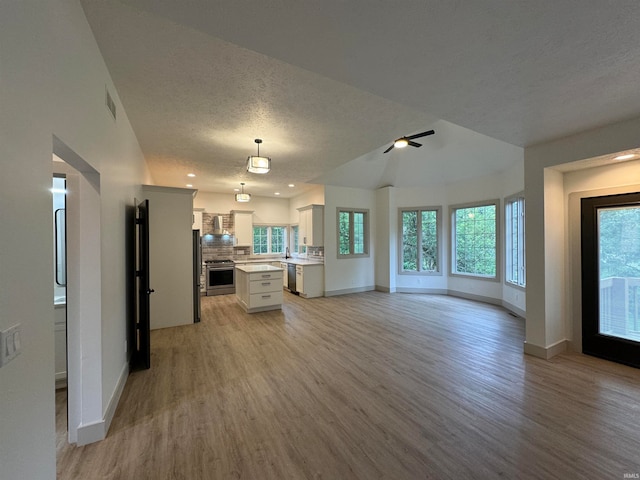 unfurnished living room featuring ceiling fan, light hardwood / wood-style flooring, and a textured ceiling