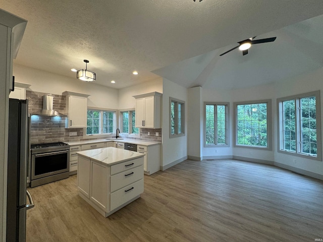 kitchen with white cabinetry, wall chimney range hood, a center island, light hardwood / wood-style floors, and stainless steel range oven