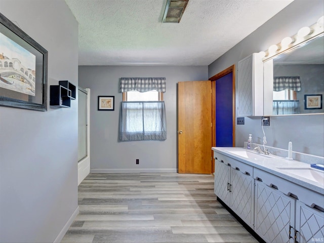 bathroom featuring a textured ceiling, wood-type flooring, and double sink vanity