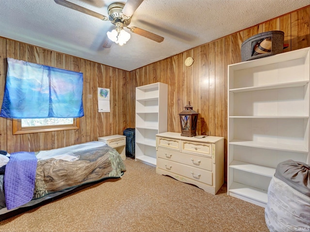 carpeted bedroom with ceiling fan, wooden walls, and a textured ceiling