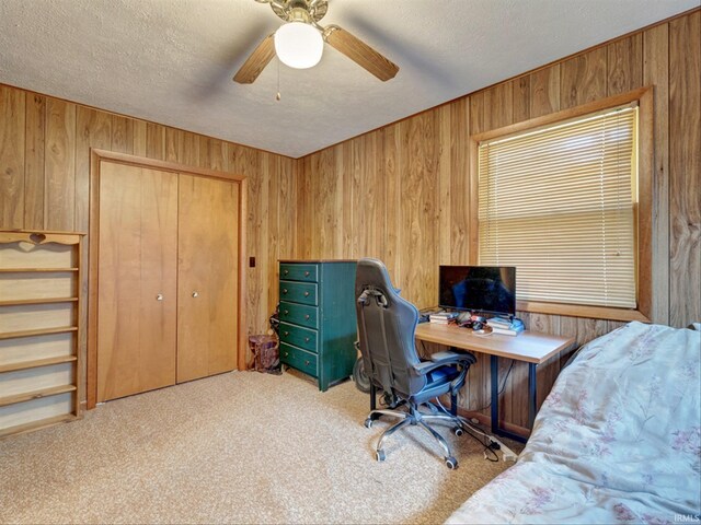 carpeted office space featuring wood walls, a textured ceiling, and ceiling fan