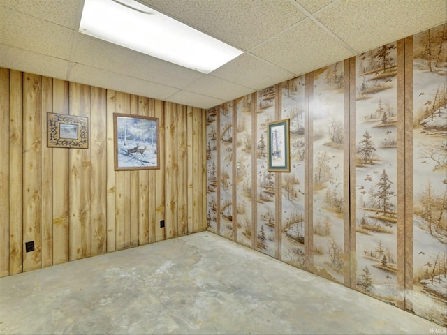 basement with a drop ceiling and wood walls