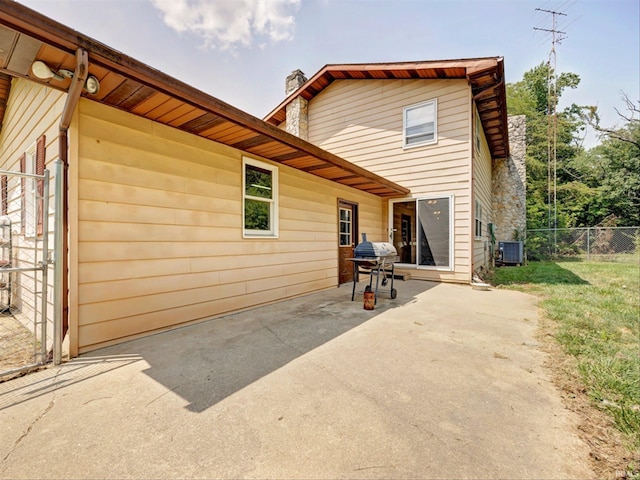 back of property with central AC unit and a patio