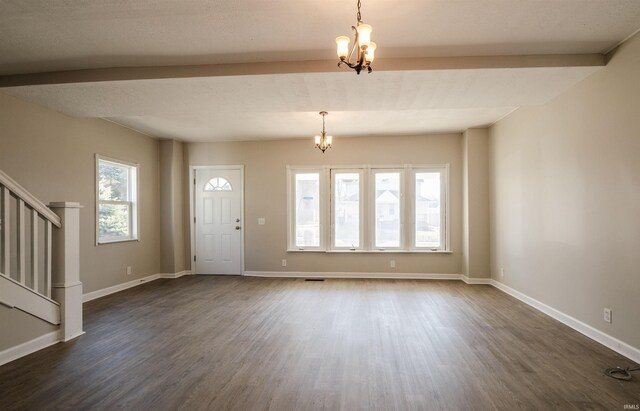 entryway with dark wood-type flooring, a notable chandelier, and a wealth of natural light