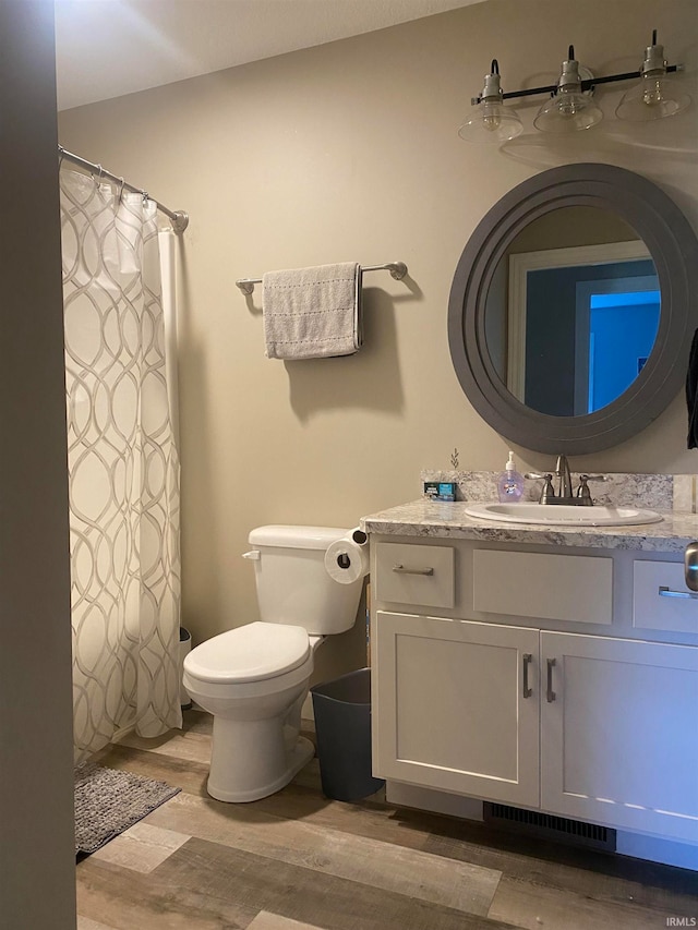 bathroom featuring wood-type flooring, vanity, and toilet