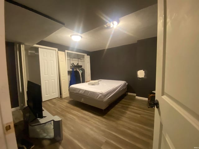 bedroom with multiple closets and hardwood / wood-style flooring