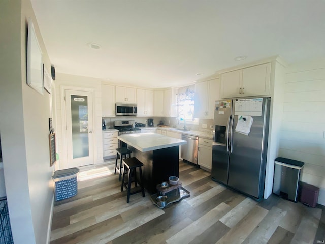 kitchen featuring appliances with stainless steel finishes, white cabinetry, a center island, and hardwood / wood-style floors