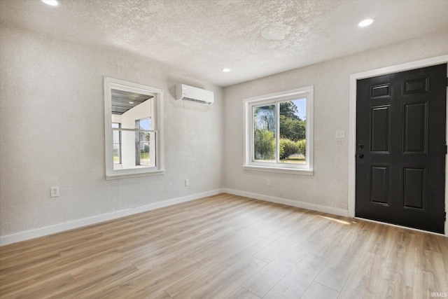 entrance foyer with a wall mounted AC, light wood-type flooring, and plenty of natural light