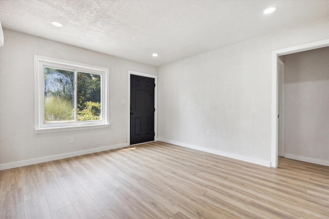 spare room with light wood-type flooring and a textured ceiling