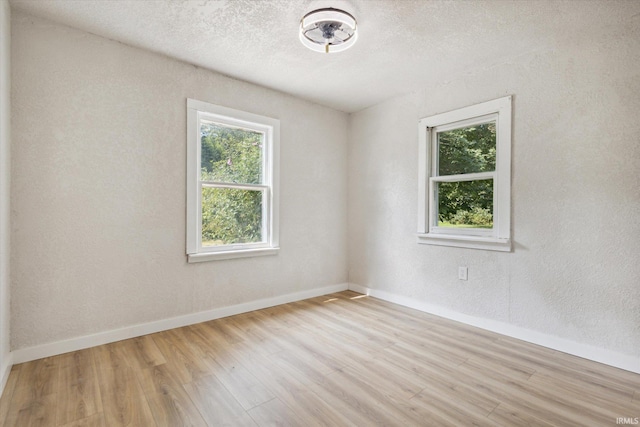 spare room featuring light hardwood / wood-style flooring and a textured ceiling