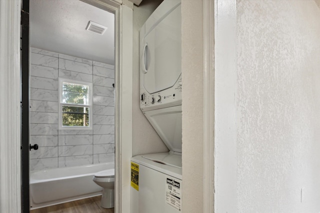 washroom featuring stacked washer and clothes dryer and wood-type flooring