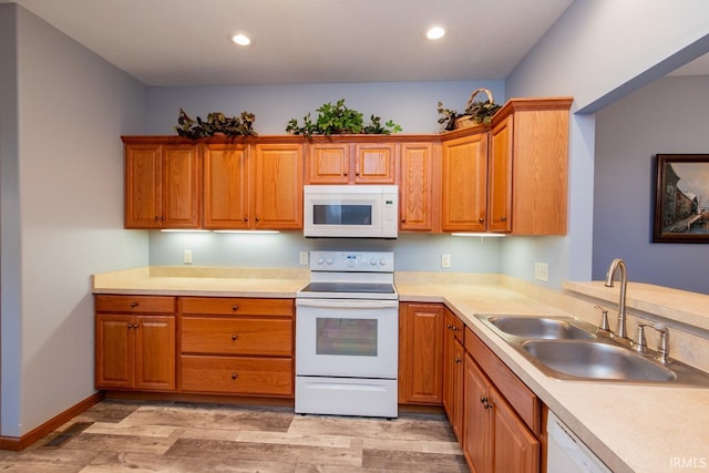 kitchen with light wood-type flooring, white appliances, and sink