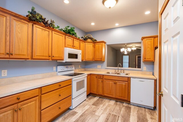 kitchen featuring an inviting chandelier, sink, light wood-type flooring, and white appliances