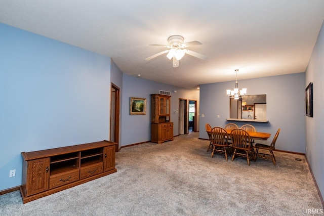 dining space with ceiling fan with notable chandelier and carpet flooring