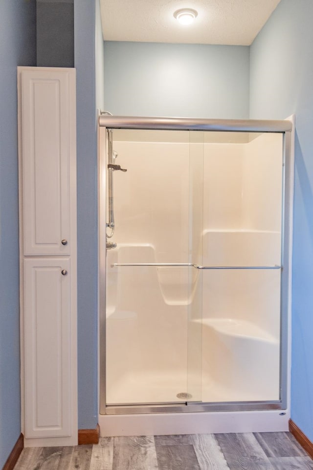 bathroom with an enclosed shower, a textured ceiling, and hardwood / wood-style floors