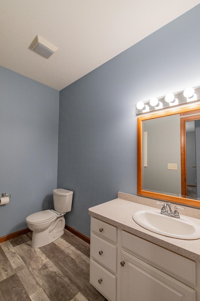 bathroom with hardwood / wood-style flooring, toilet, and vanity