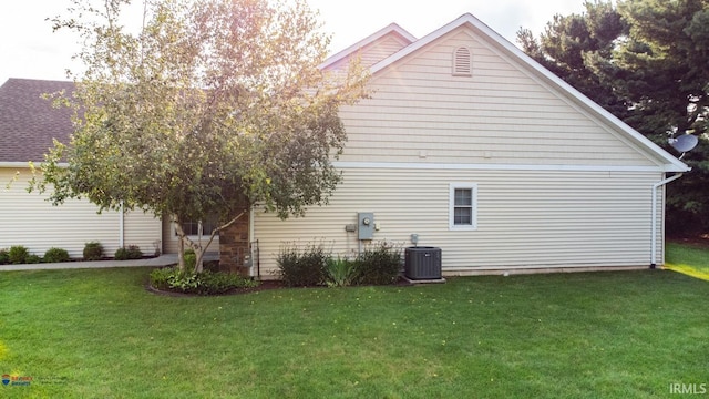 view of side of property with central AC and a lawn