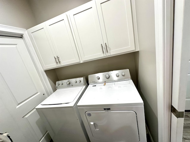 laundry room featuring cabinets, washing machine and dryer, and hardwood / wood-style floors