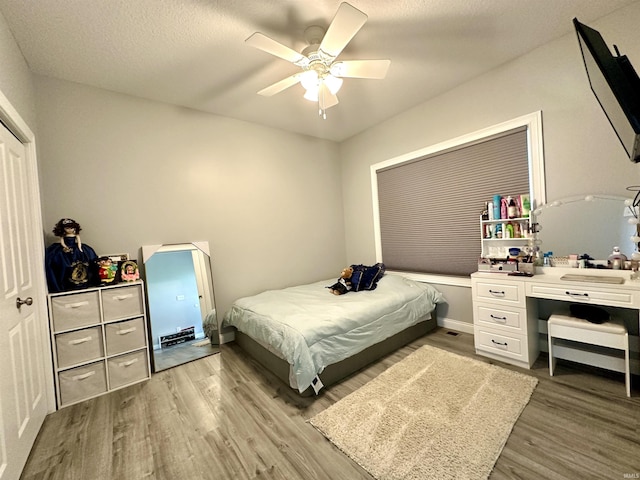 bedroom with hardwood / wood-style floors, a textured ceiling, and ceiling fan