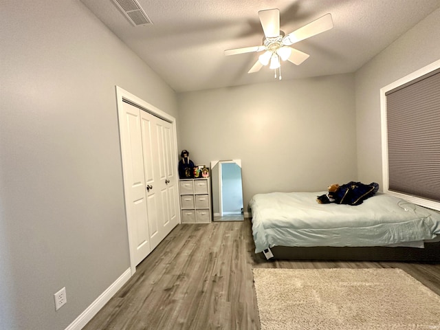 bedroom featuring hardwood / wood-style floors, a textured ceiling, ceiling fan, and a closet