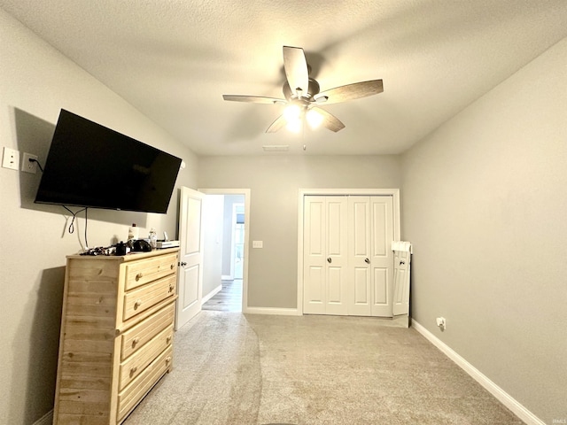 bedroom with light carpet, a textured ceiling, a closet, and ceiling fan