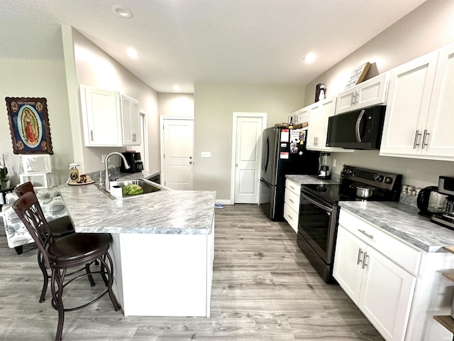 kitchen with white cabinetry, sink, a kitchen breakfast bar, kitchen peninsula, and stainless steel appliances