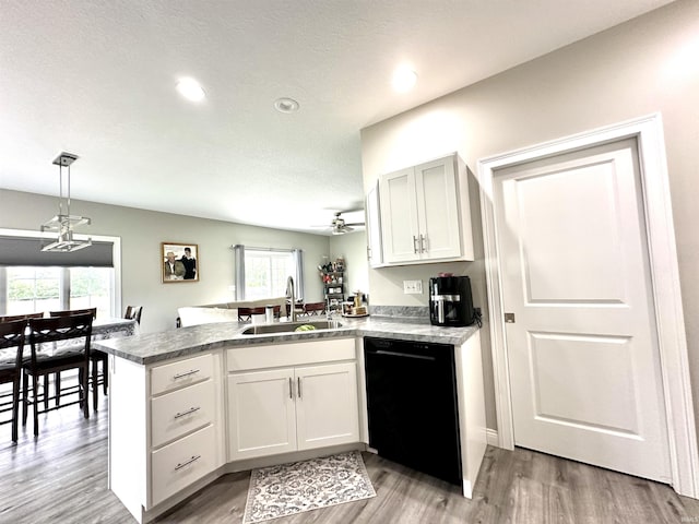 kitchen featuring black dishwasher, sink, kitchen peninsula, and white cabinets