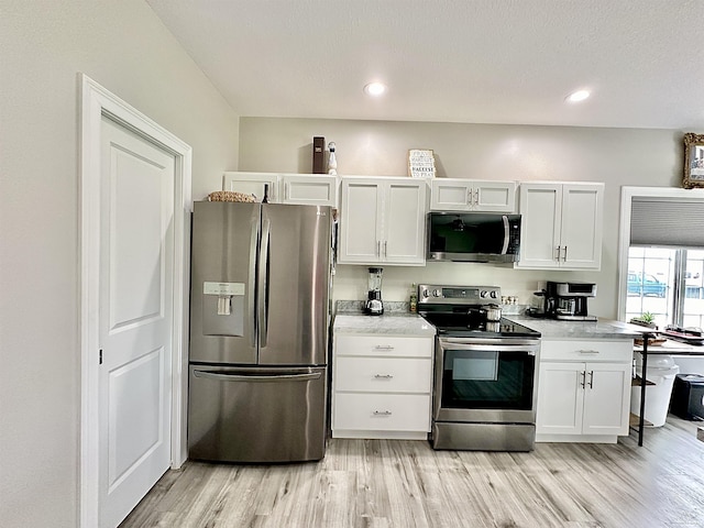 kitchen featuring appliances with stainless steel finishes, light hardwood / wood-style flooring, and white cabinets