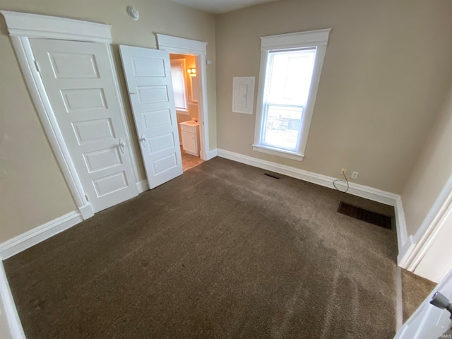 unfurnished bedroom with ensuite bathroom and carpet flooring