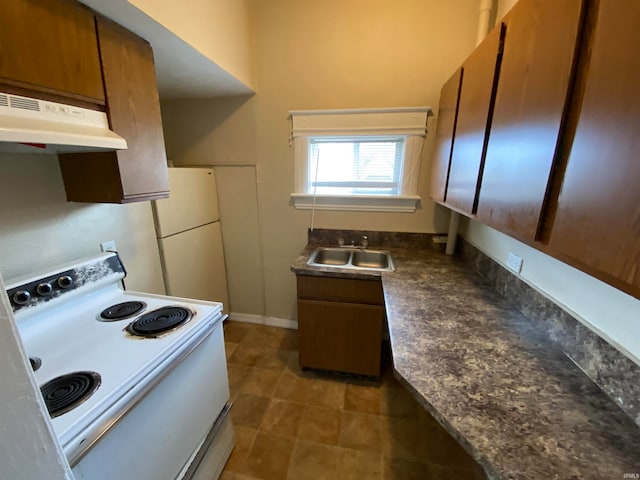 kitchen featuring dark tile patterned floors, white refrigerator, stove, and sink