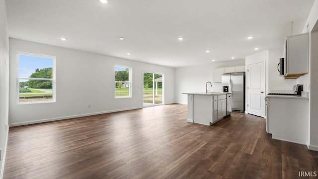 kitchen featuring dark wood-type flooring, appliances with stainless steel finishes, sink, and a kitchen island with sink