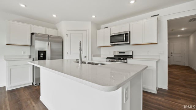 kitchen featuring white cabinets, appliances with stainless steel finishes, dark hardwood / wood-style flooring, an island with sink, and sink