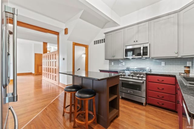 kitchen featuring gray cabinets, visible vents, decorative backsplash, appliances with stainless steel finishes, and light wood-type flooring