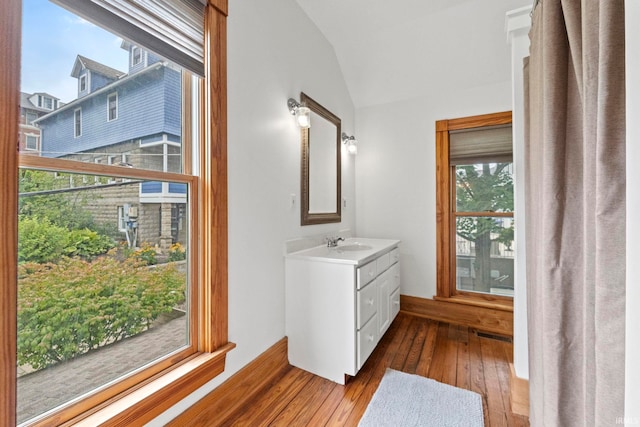 bathroom featuring hardwood / wood-style flooring, visible vents, vaulted ceiling, and vanity