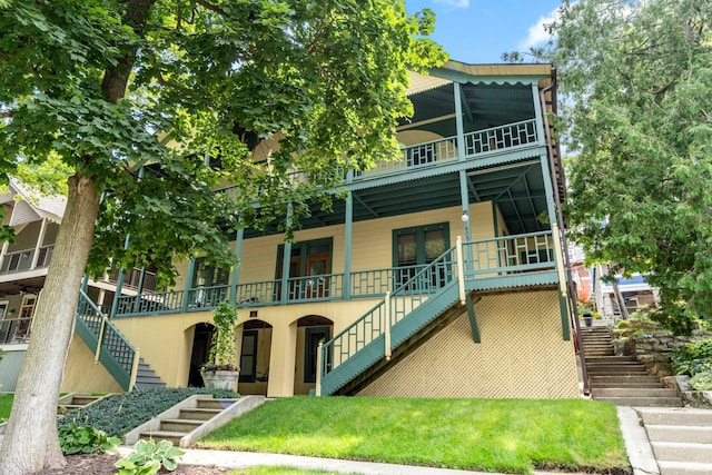 view of front facade featuring stairs, covered porch, and a front yard